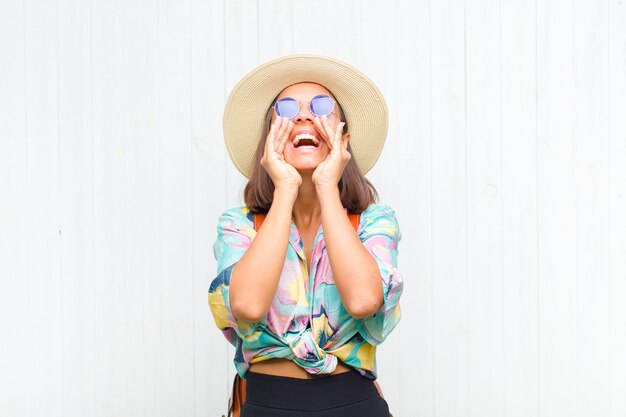 Foto mulher latina se sentindo feliz, animada e positiva, dando um grande grito com as mãos perto da boca, gritando