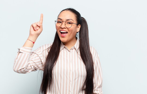 mulher latina se sentindo um gênio feliz e animado depois de realizar uma ideia, levantando o dedo alegremente, eureka!