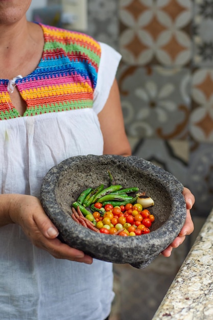 Mulher latina segurando um molcajete mexicano tradicional com pimenta e legumes