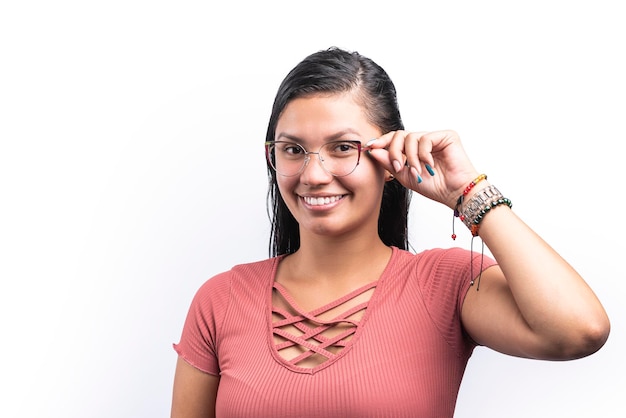 mulher latina sorridente com óculos olhando para a câmera no fundo branco