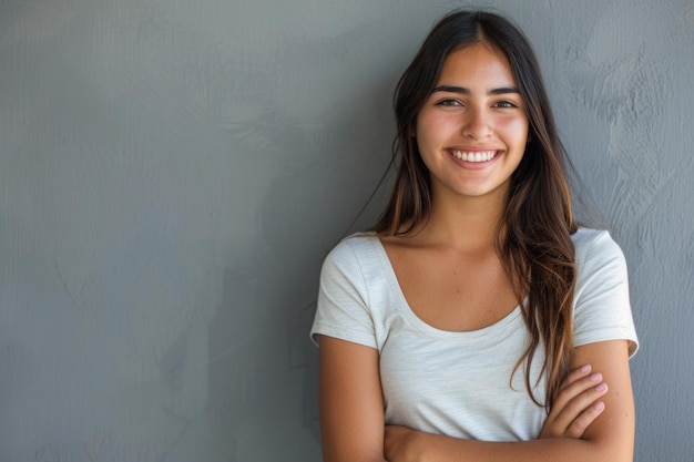 Mulher latina sorridente com os braços cruzados em fundo cinzento