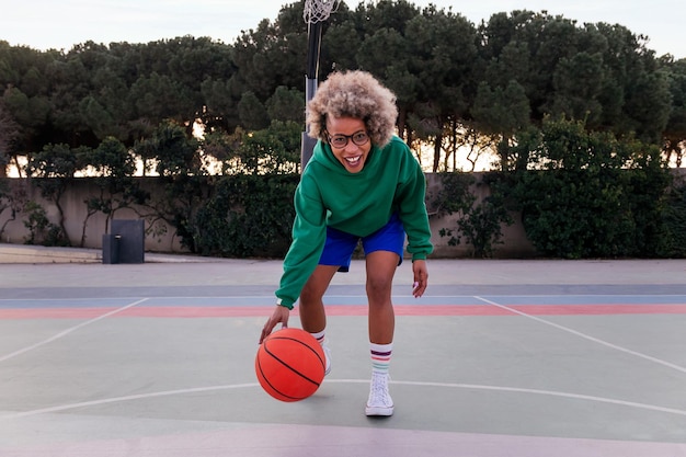 Mulher latina sorridente jogando na quadra de basquete em um conceito de parque urbano de esporte urbano no espaço de cópia de rua para texto