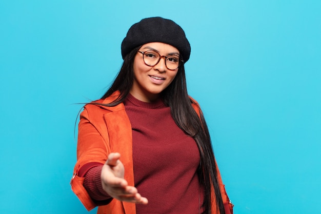 Mulher latina sorrindo, parecendo feliz, confiante e amigável, oferecendo um aperto de mão para fechar um negócio, cooperando