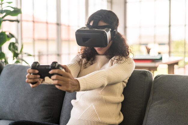 Mulher latina usando fone de ouvido de realidade virtual no sofá em casa