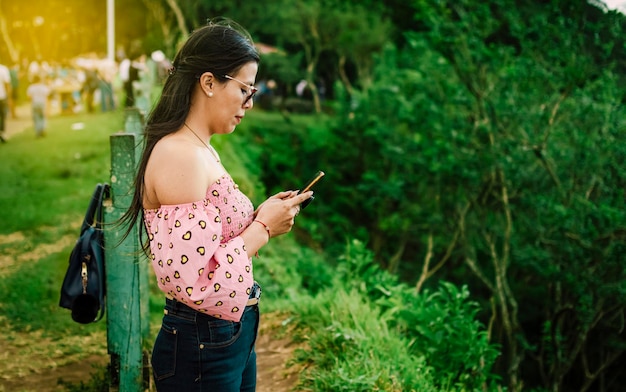 Mulher latina verificando o celular, menina bonita de óculos verificando o celular