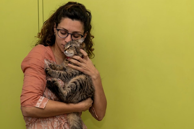 Mulher latino-americana segura em seus braços e brinca carinhosamente com seu gato