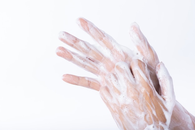 Mulher lavando as mãos com sabão no fundo branco. Conceito de saúde.