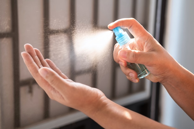 Mulher lavando as mãos com spray de álcool