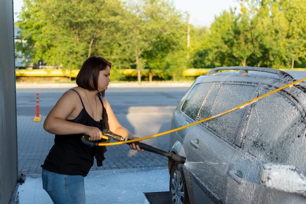 Mulher lavando carro em uma lavagem de carros de autoatendimento