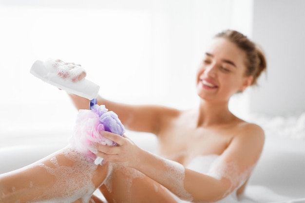 Mulher lavando com esponja relaxante no banho