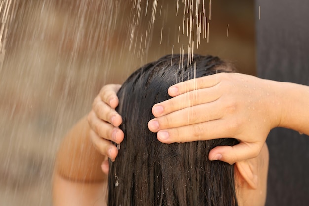 Mulher lavando o cabelo no chuveiro ao ar livre no close up do dia de verão