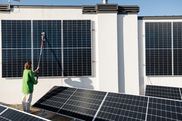 Mulher lavando painéis solares no telhado