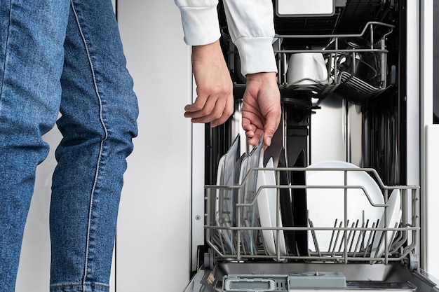 Mulher lavando pratos na máquina de lavar louça em casa