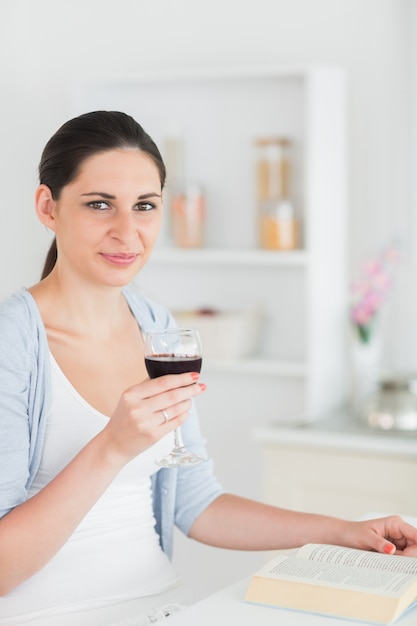 Mulher lendo e segurando copo de vinho tinto