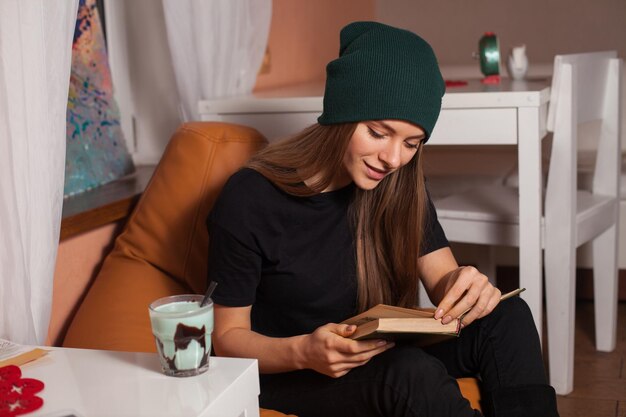 Mulher lendo livro e bebendo chá no café