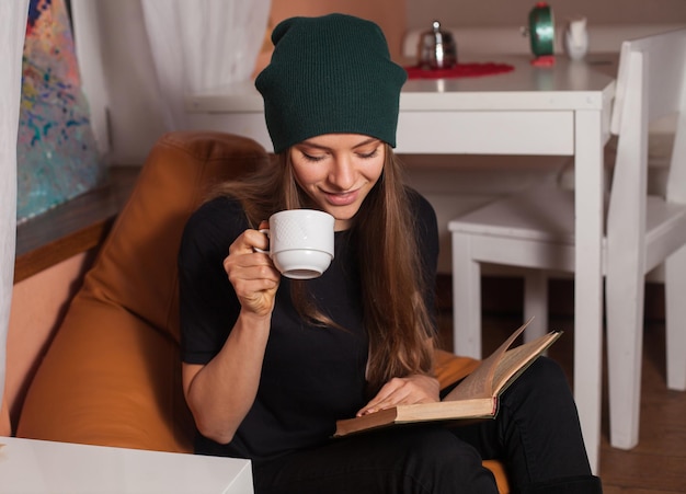 Mulher lendo livro e bebendo chá no café