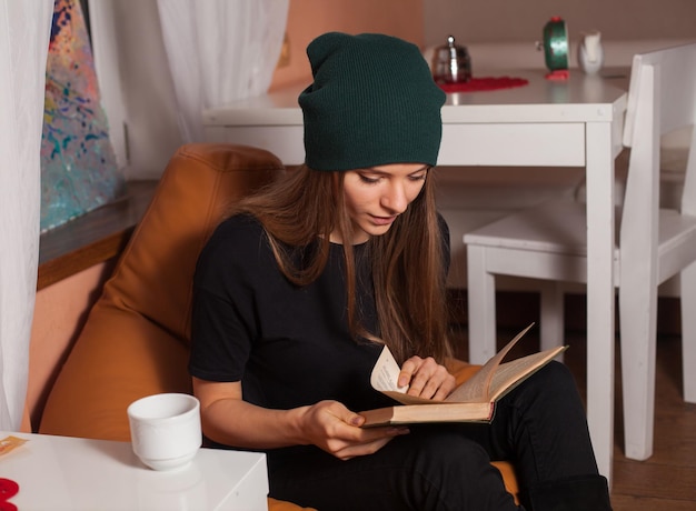 Mulher lendo livro e bebendo chá no café