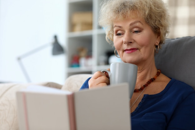 Mulher lendo livro e beber chá de ervas agailnst