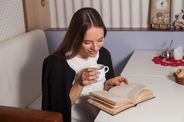 Mulher lendo livro no café e bebendo chá