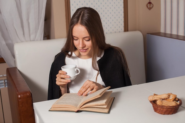 Mulher lendo livro no café e bebendo chá