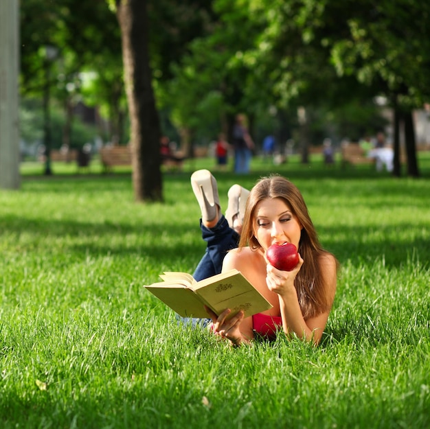 Mulher lendo livro no parque na grama