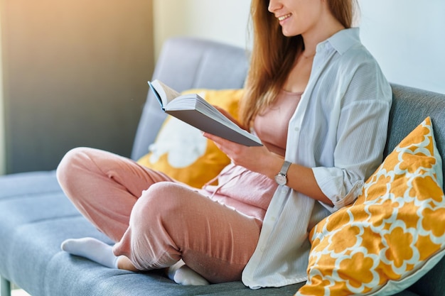 Mulher lendo romance enquanto descansava em um sofá em casa