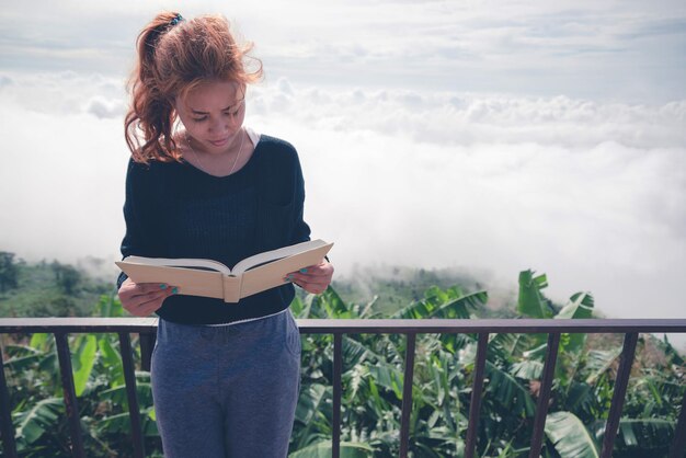 Mulher lendo um livro contra o céu