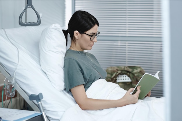 Mulher lendo um livro deitado na enfermaria do hospital