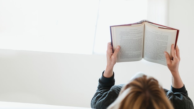 Foto mulher lendo um livro na cama durante a quarentena de coronavírus