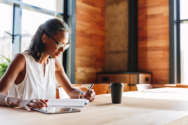 Foto mulher lendo um livro sentada à mesa