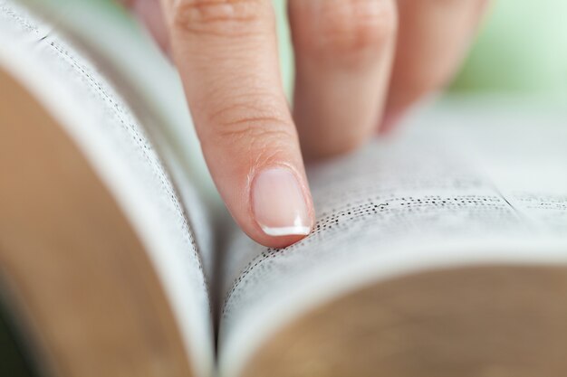 Mulher lendo um livro velho e pesado no fundo, close-up