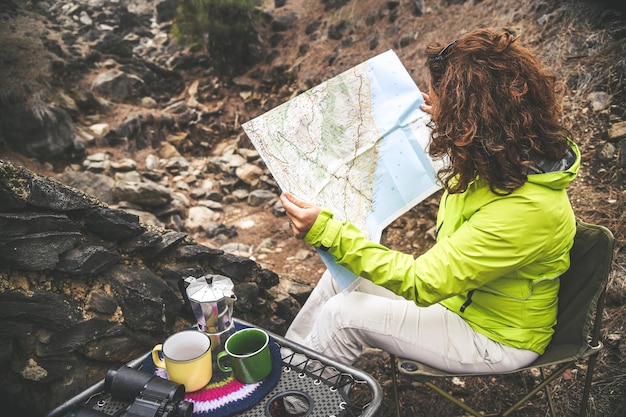 Foto mulher lendo um mapa sentada em uma cadeira na floresta