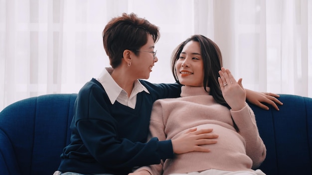 Mulher lésbica asiática grávida e seu parceiro ficam felizes em passar algum tempo juntos em casa.