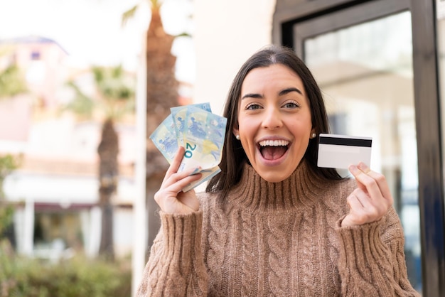 Mulher levando muito dinheiro e cartão de crédito ao ar livre