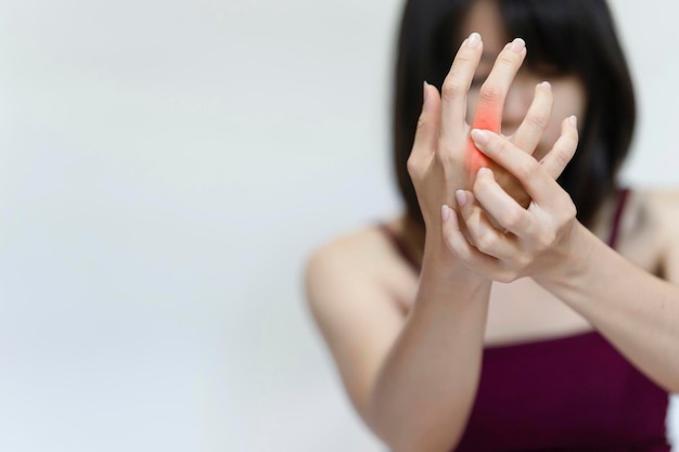 Foto mulher levantando a mão e segurando o dedo devido à dor da artrite reumatóide.