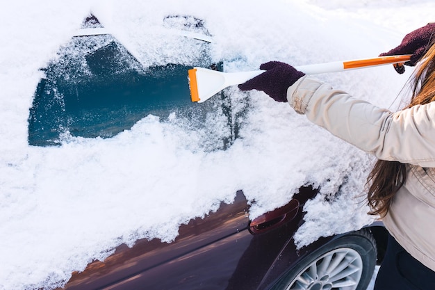 Mulher limpa a neve das janelas do carro