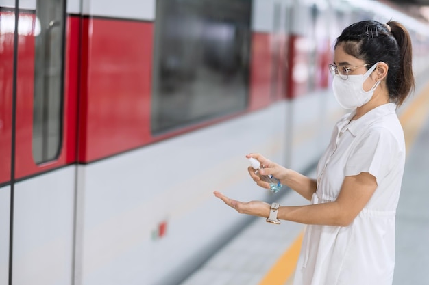 Mulher limpa as mãos por álcool gel desinfetante no trem ou transporte público, proteção contra infecção por doença de coronavirus. higiene pessoal, segurança e transporte em viagens de acordo com os conceitos covid-19