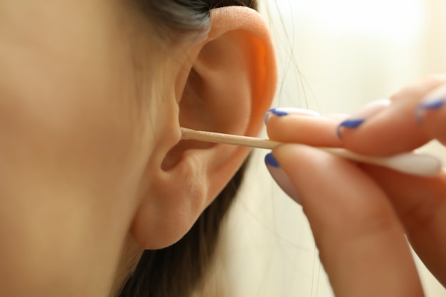 Mulher limpa as orelhas com um cotonete, close-up