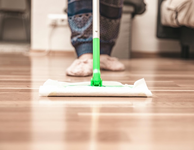Mulher limpando o chão usando esfregão em casa