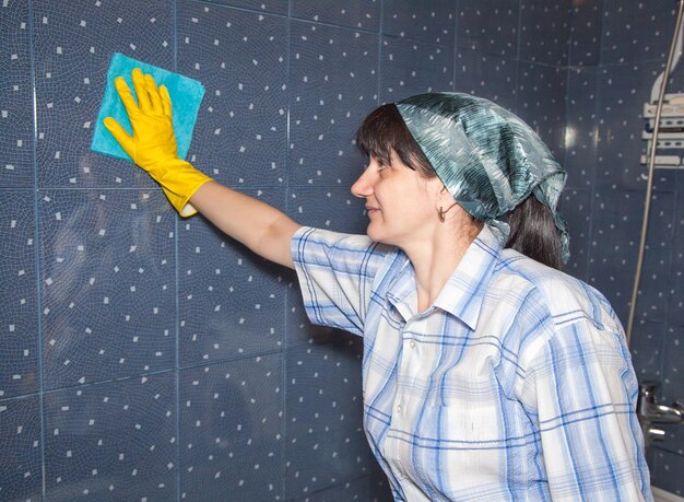 Mulher limpando parede de azulejos