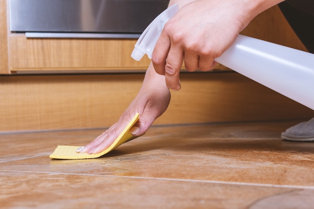 Foto mulher limpando piso de cerâmica com spray especial