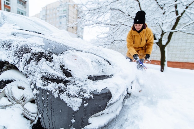Mulher limpando seu carro de neve após a tempestade de neve