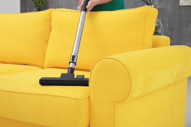 Foto mulher limpando sofá com aspirador de pó em casa