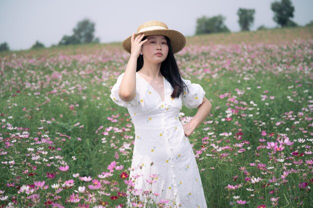 Mulher linda asiática com vestido branco no jardim de flores