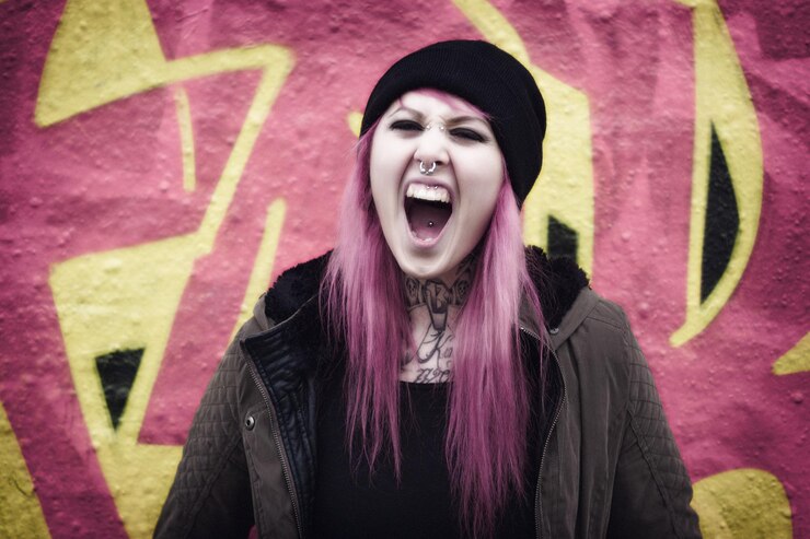 Foto mulher linda com cabelo tingido gritando contra a parede de graffiti