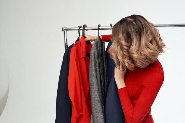 Mulher linda com uma jaqueta vermelha perto do guarda-roupa de retalho fundo claro foto de alta qualidade