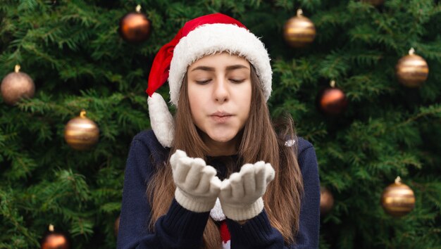 Mulher linda de Natal mandando um beijo para você contra o fundo da árvore de natal