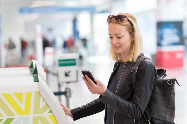 Foto mulher linda de pé junto à caixa eletrônica no aeroporto