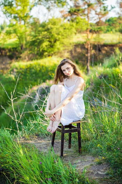 Mulher linda em um vestido branco em uma cadeira