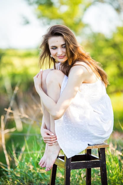 Mulher linda em um vestido branco em uma cadeira